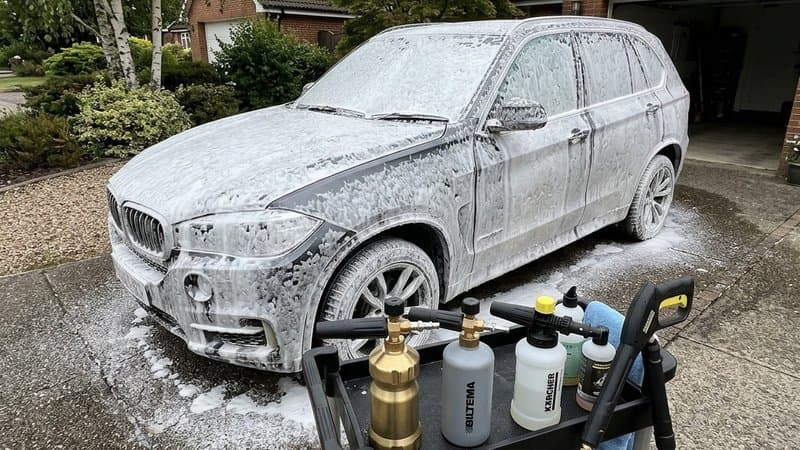 Flera olika skumkanoner och foam lances monterade på högtryckstvättar med tjockt vitt skum på en bil.